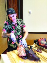 Dustin Patrick, creator of the event, cutting into the smoked pig.
