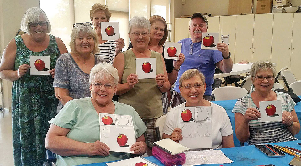 The Fine Arts Guild closed out its 2016-2017 season with a Colored Pencil Class. Nine of the 15 students are pictured above with their colored pencil painting of an apple.