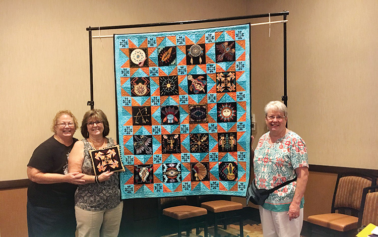Pictured from left to right: Robin Tisinger, Diane Williams, Marie Stuersel. Robin and Marie, along with Patty Foley and 2019 Raffle Quilt Chair Sharon Haworth, embroidered the quilt blocks. Sewing the blocks together and machine quilting was completed by Sharon Haworth.